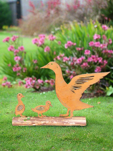 Rusty metal duck and two ducklings displayed on a log of wood