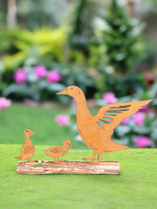 Rusty metal duck and two ducklings displayed on a log of wood