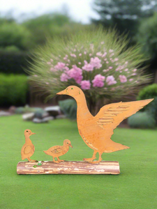 Rusty metal duck and two ducklings displayed on a log of wood